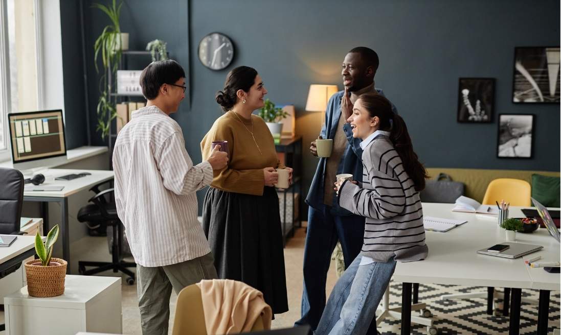 Groupe de quatre personnes debout dans un bureau discutent ensemble