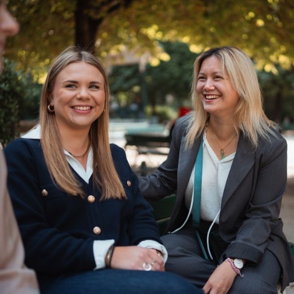 Deux jeunes femmes blondes en tenues professionnelles dans un parc discutent ensemble