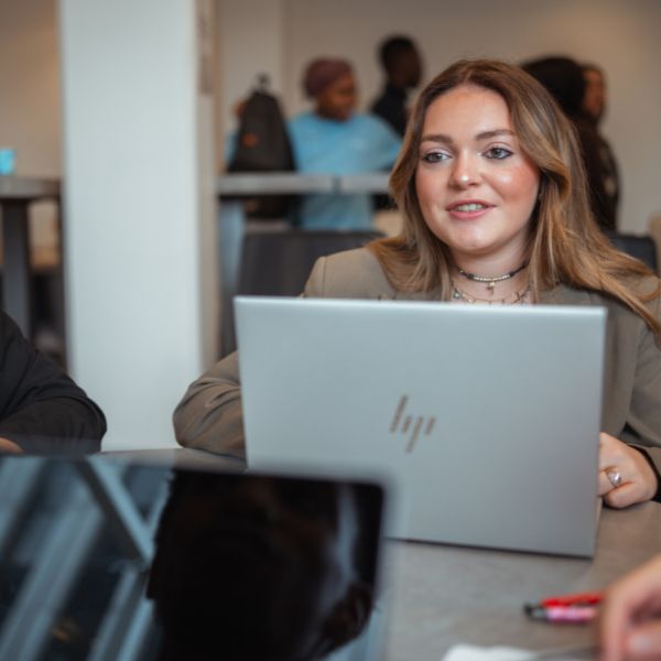 Jeune femme blonde assise devant un bureau avec un ordinateur portable